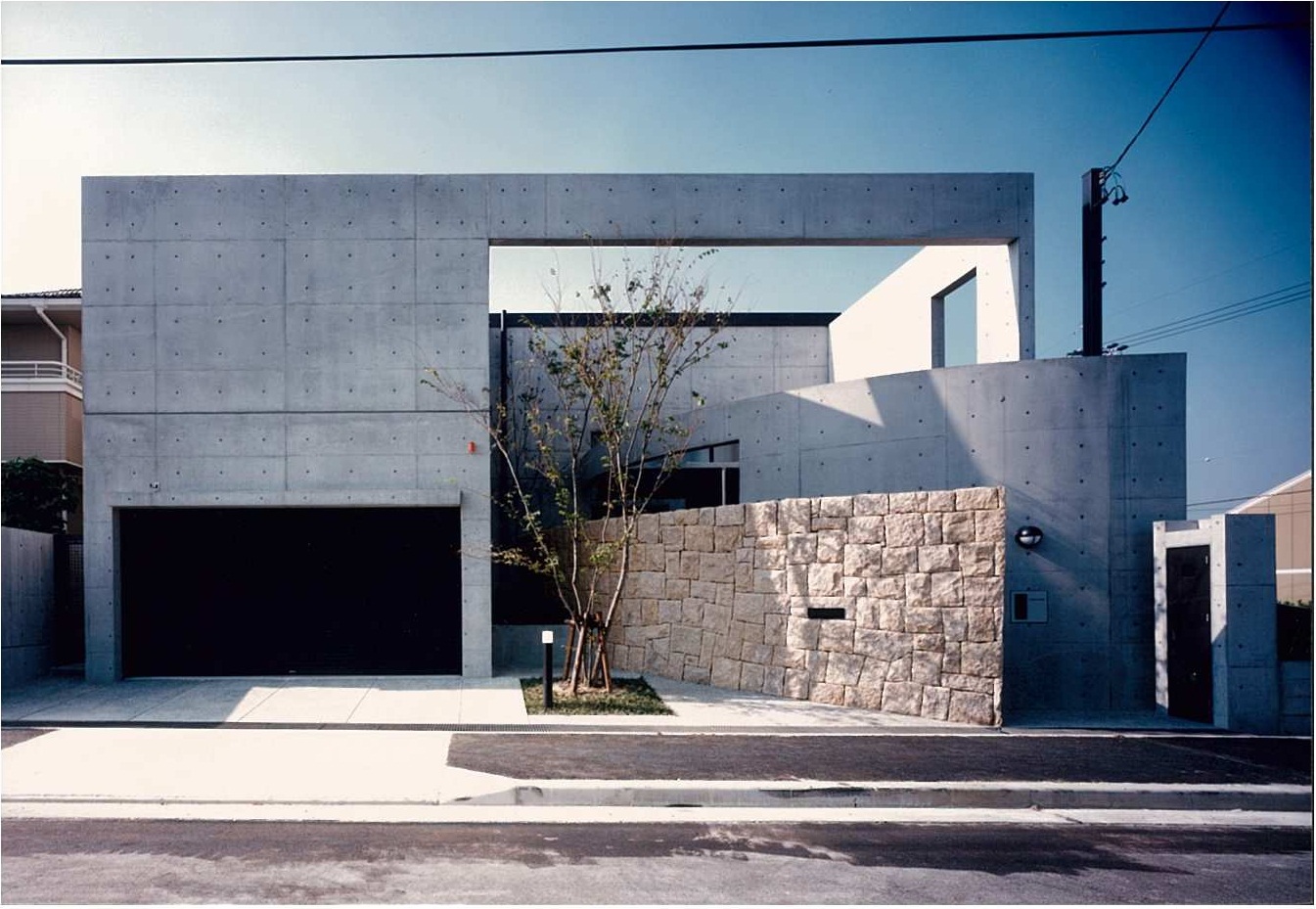 正方形のプランに石とコンクリート打放しの壁で構成されたシンプルなデザイン