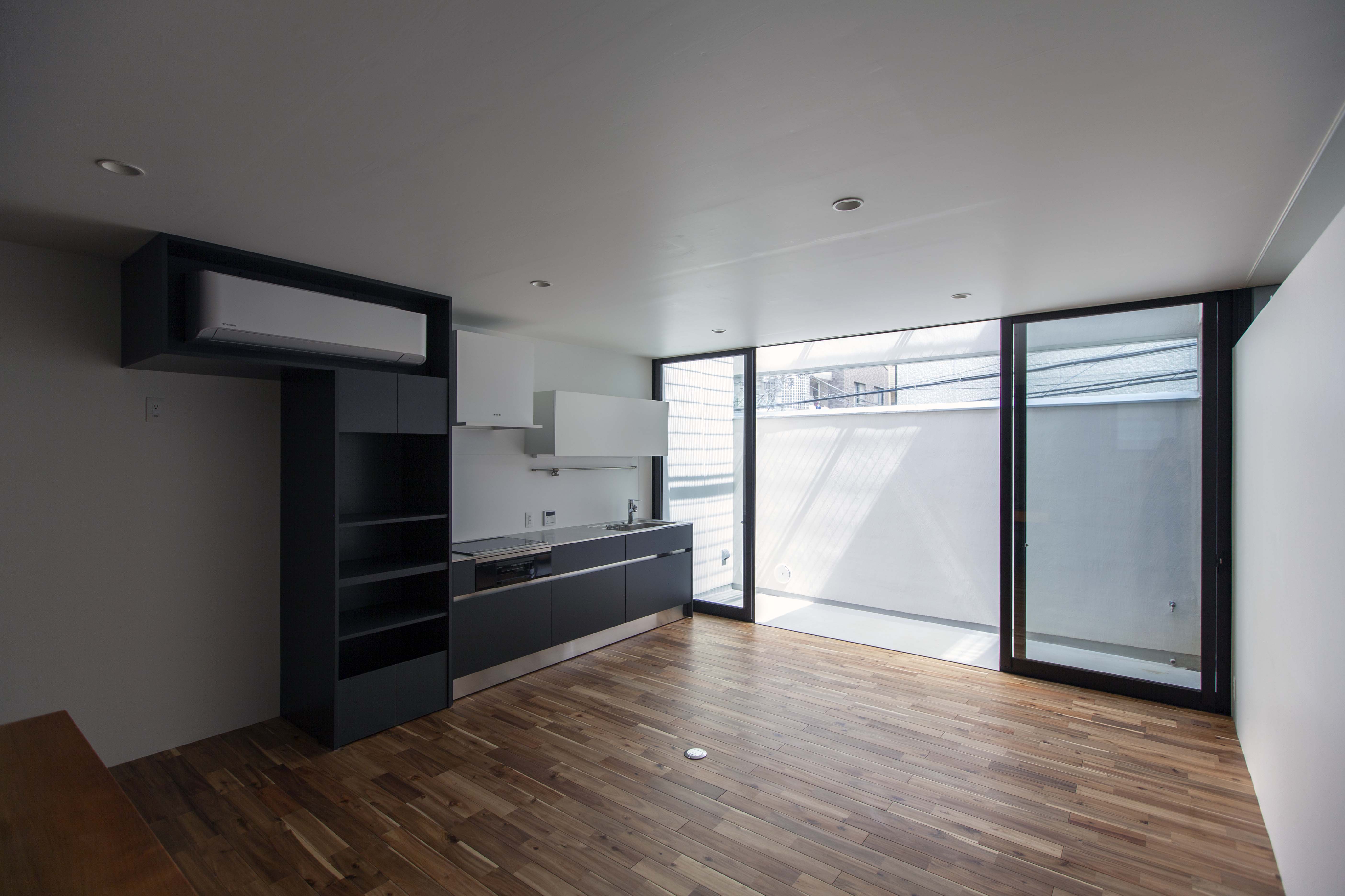 2F両親のLDKは上階とスリット窓の光が白壁に反射し、室内に光を行き渡らせている