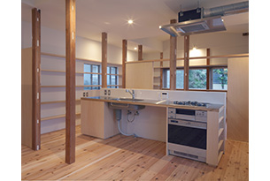 料理好きのご家族のためのキッチンは、木とステンレスで居間の中央に作られました。