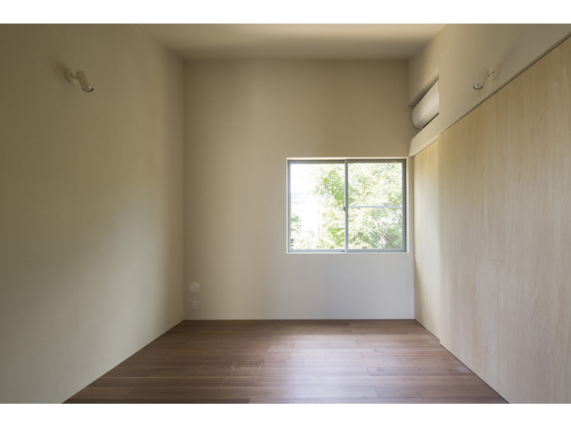 珪藻土の壁と緑の見える窓のある主寝室