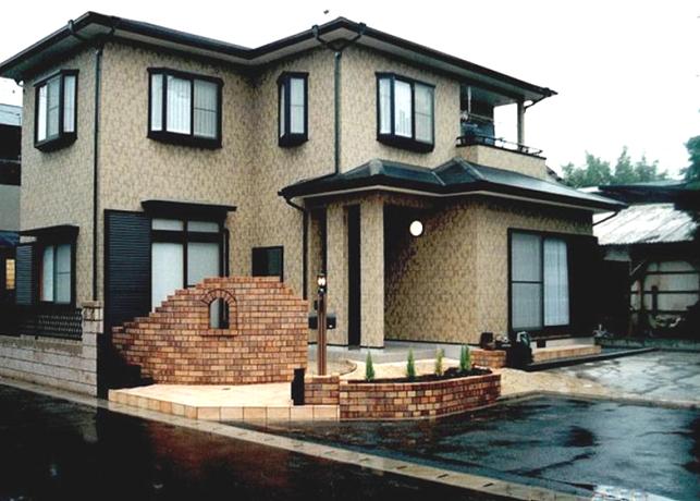 明るい色調のブリック門柱と花壇で囲まれたアプローチ