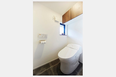 石調のフロアタイルを採用したトイレ。棚は住まい全体の統一感を演出するお色に