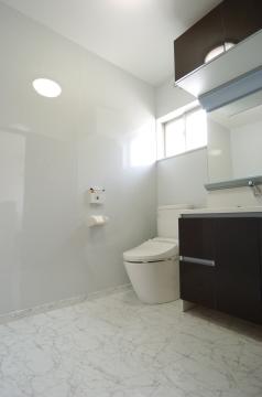 大理石調の床がモダンで清潔な空間を演出した、高級感あふれるトイレ。
