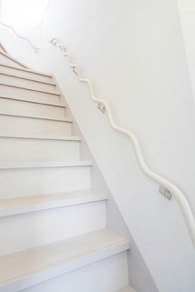 ホールに合わせて白を基調にした階段は、明るく2階まで導いてくれる空間に。波型手す