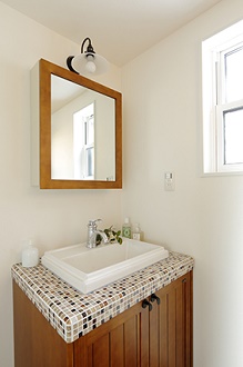 白い壁と相性のいい無垢材とタイルを使用した洗面台。