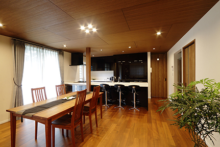 キッチンの濃色とチーク突板貼りの天井とマッチする、シックなダイニング空間。